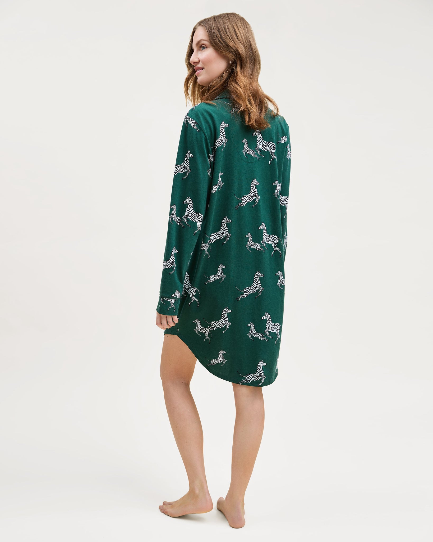 Woman wearing a green nightshirt with zebra pattern on a white background