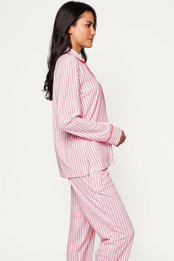 Woman wearing a pink and white striped pajama set on a light gray background