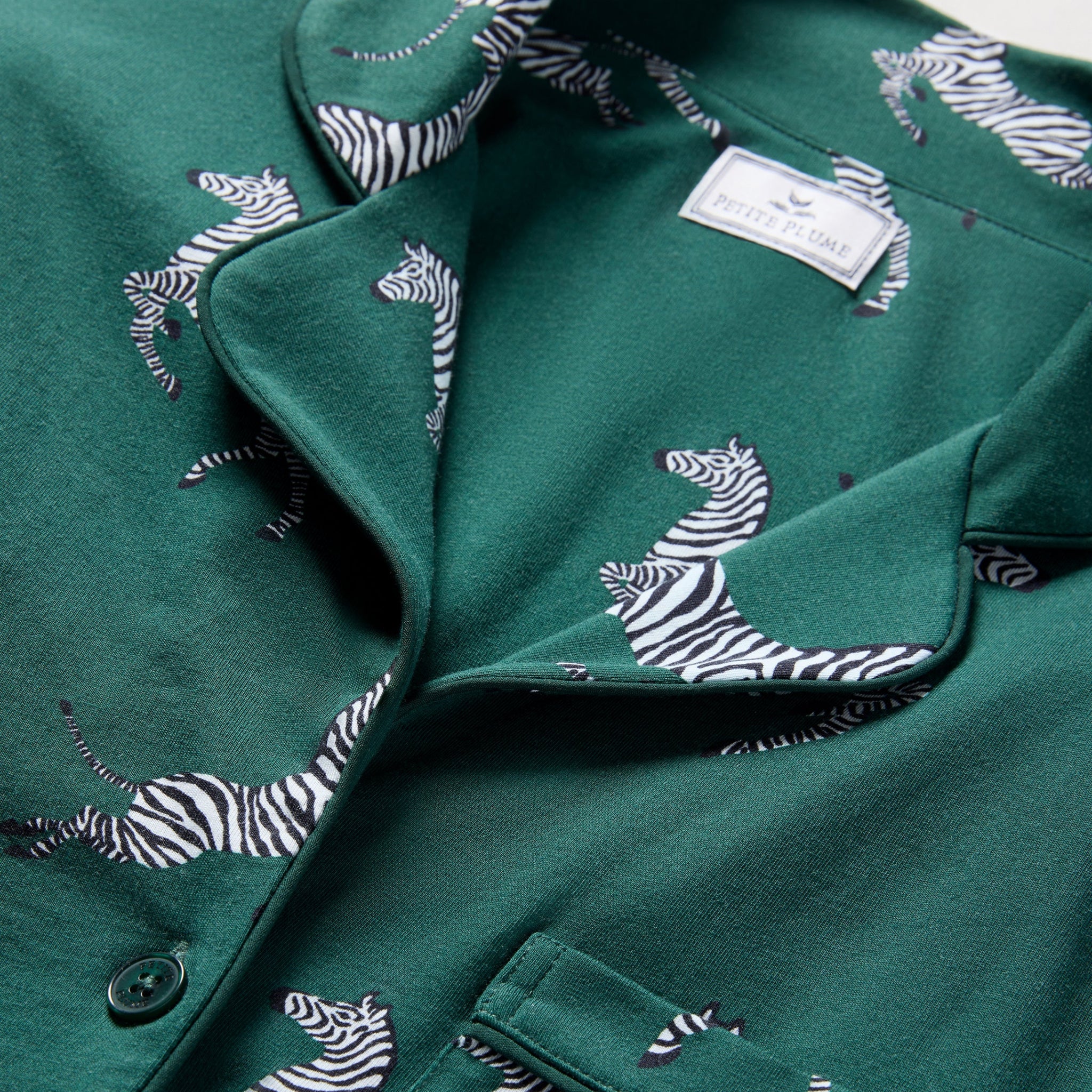 Green coat with zebra pattern and brand label on a white background