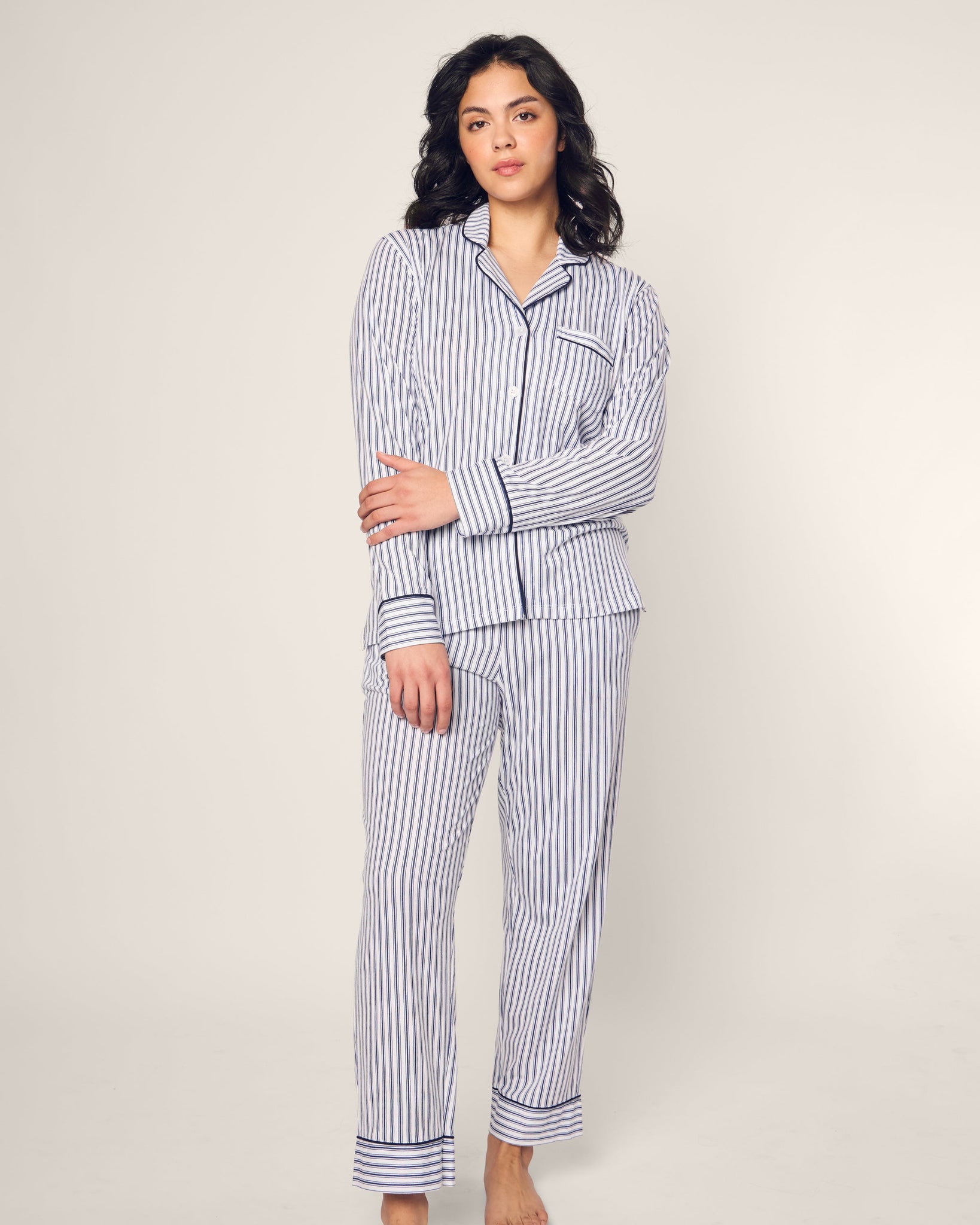 Woman wearing a blue and white striped pajama set against a plain background 
