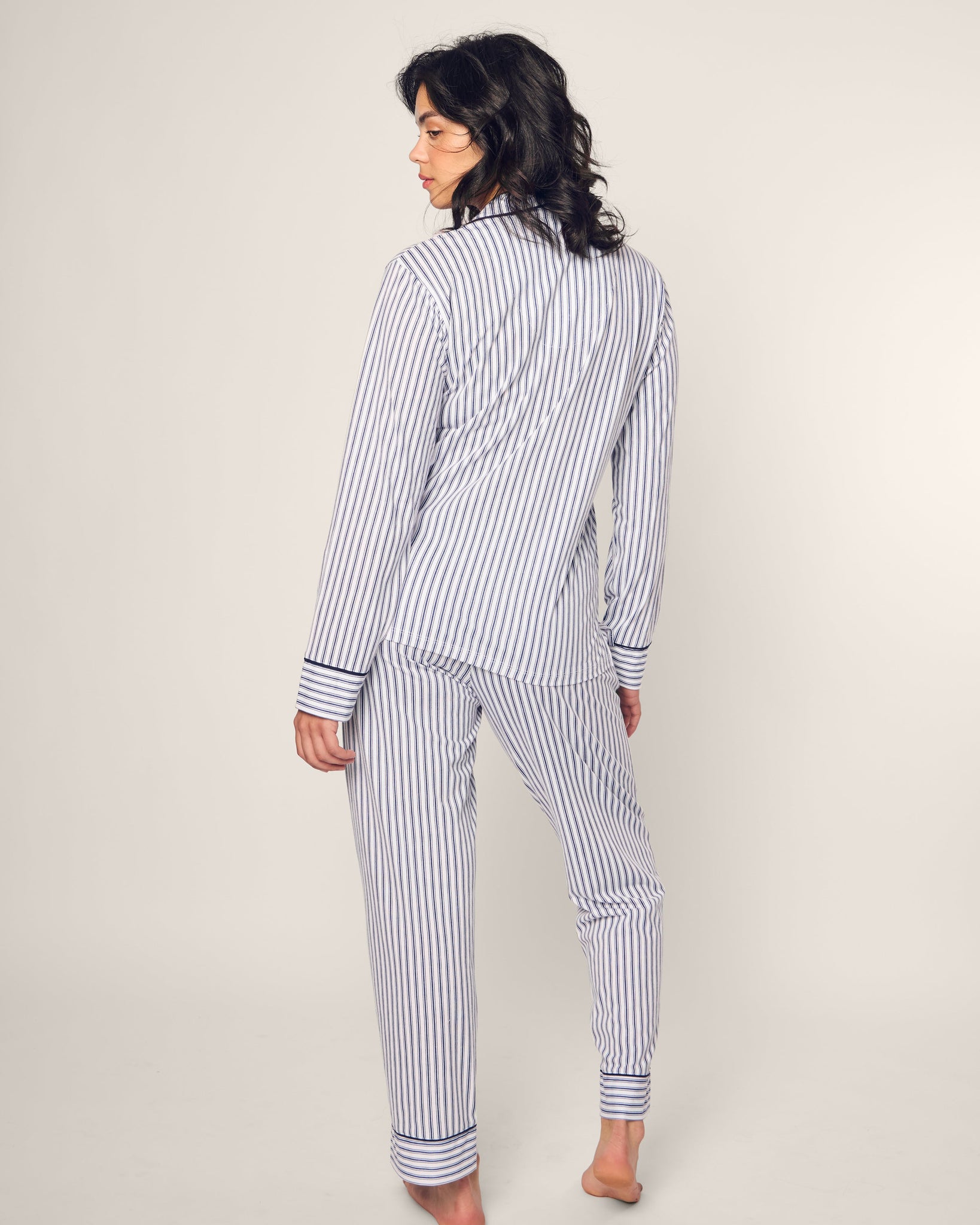 Woman wearing a blue and white striped pajama set against a plain background