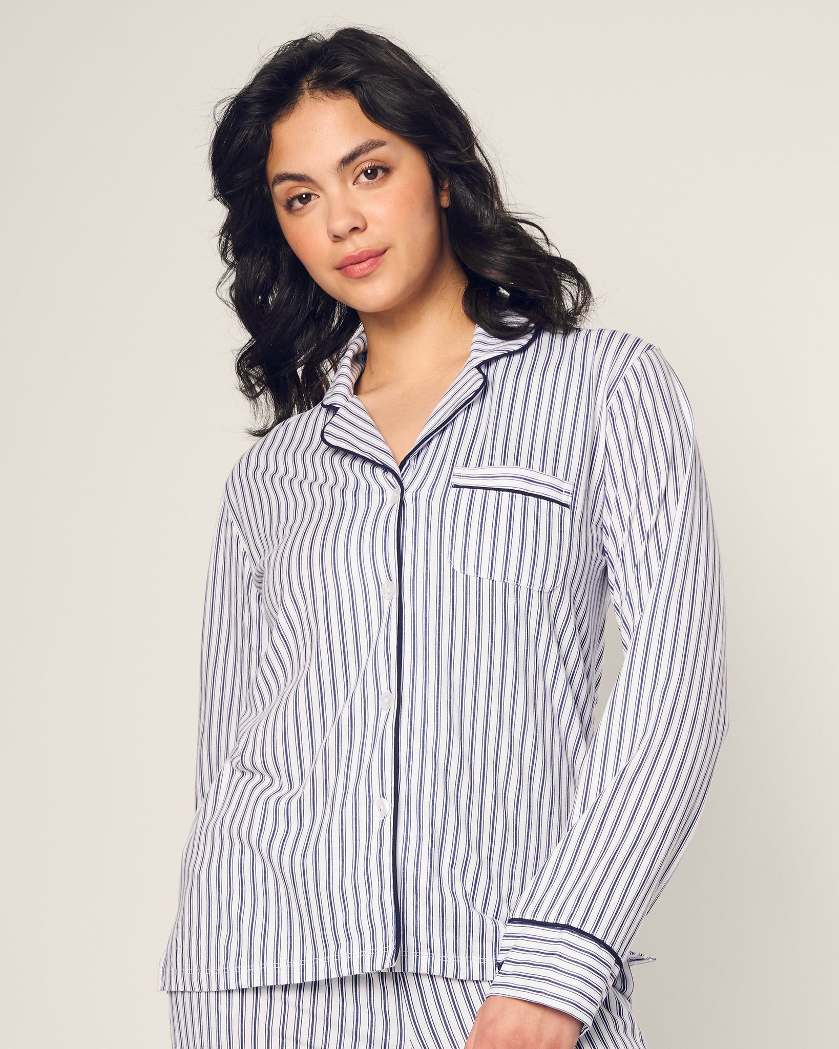 Woman wearing a striped pajama set against a plain background