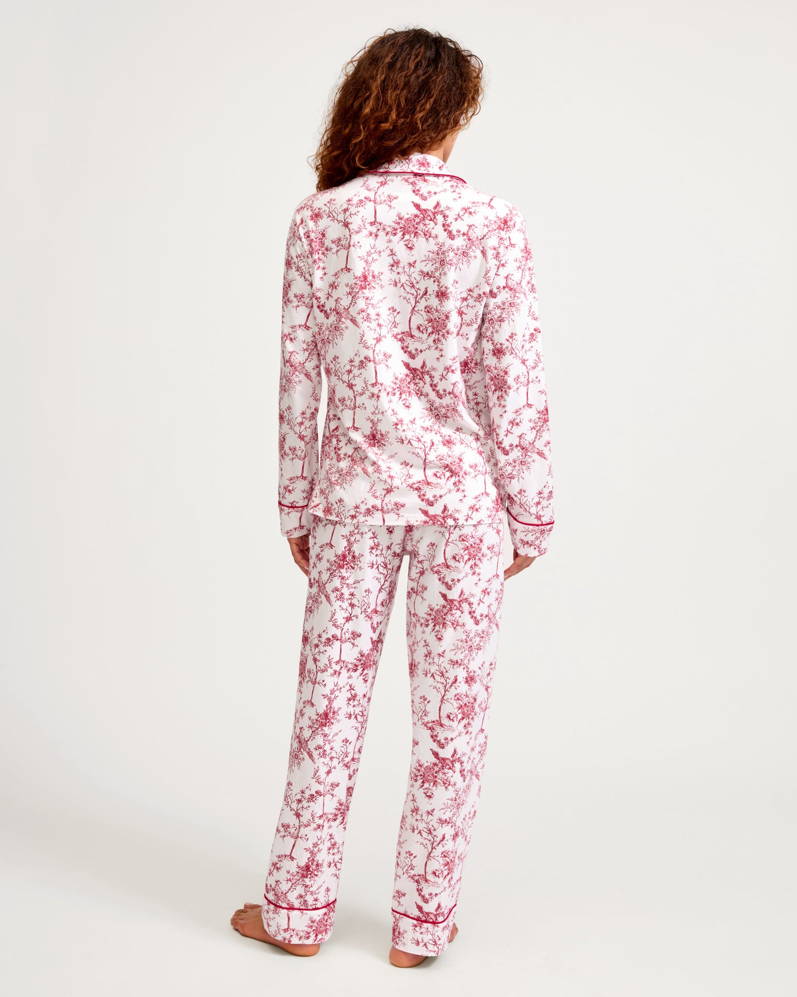 Person wearing a red and white floral pajama set on a white background