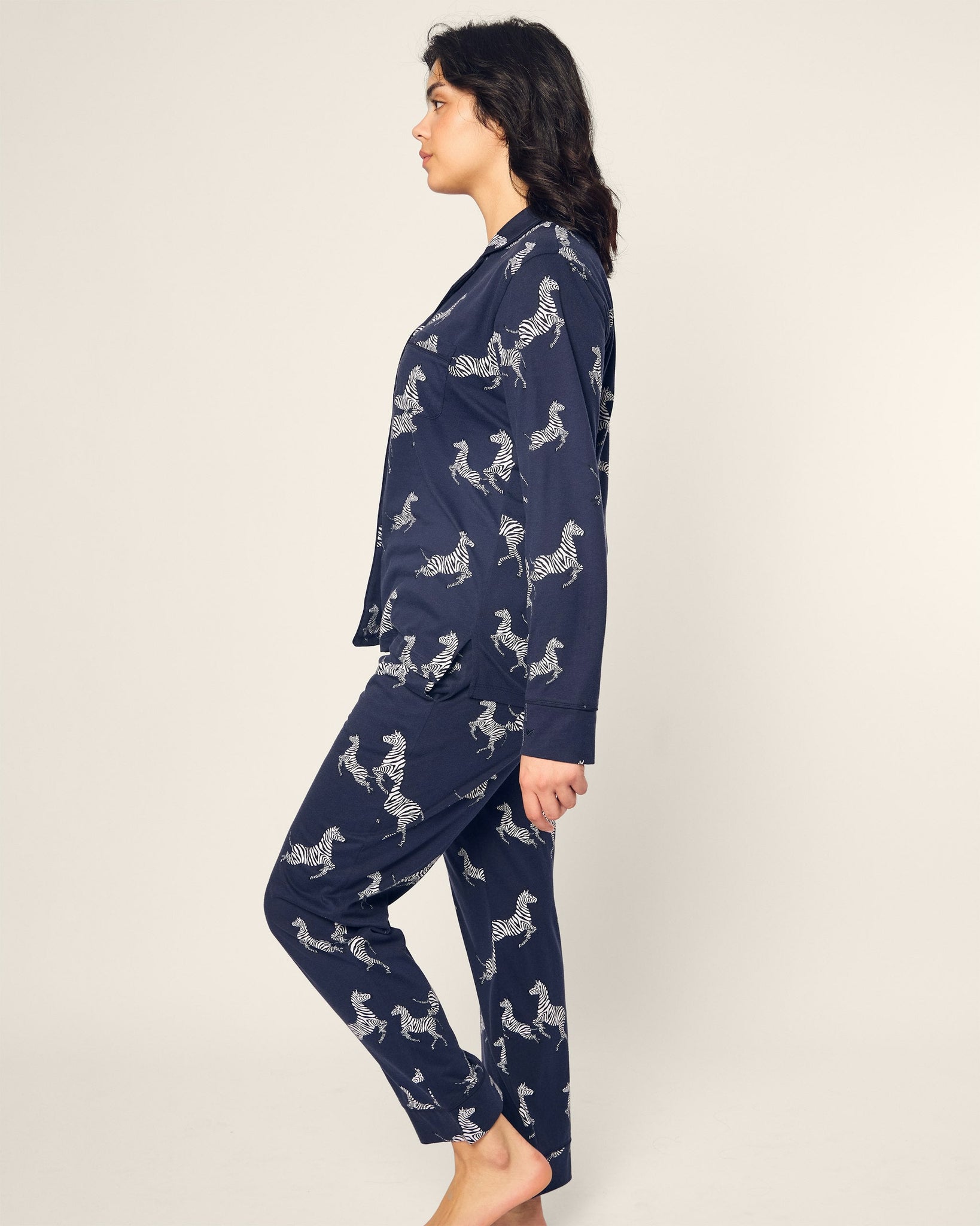Woman wearing a navy blue pajama set with zebra pattern on a white background