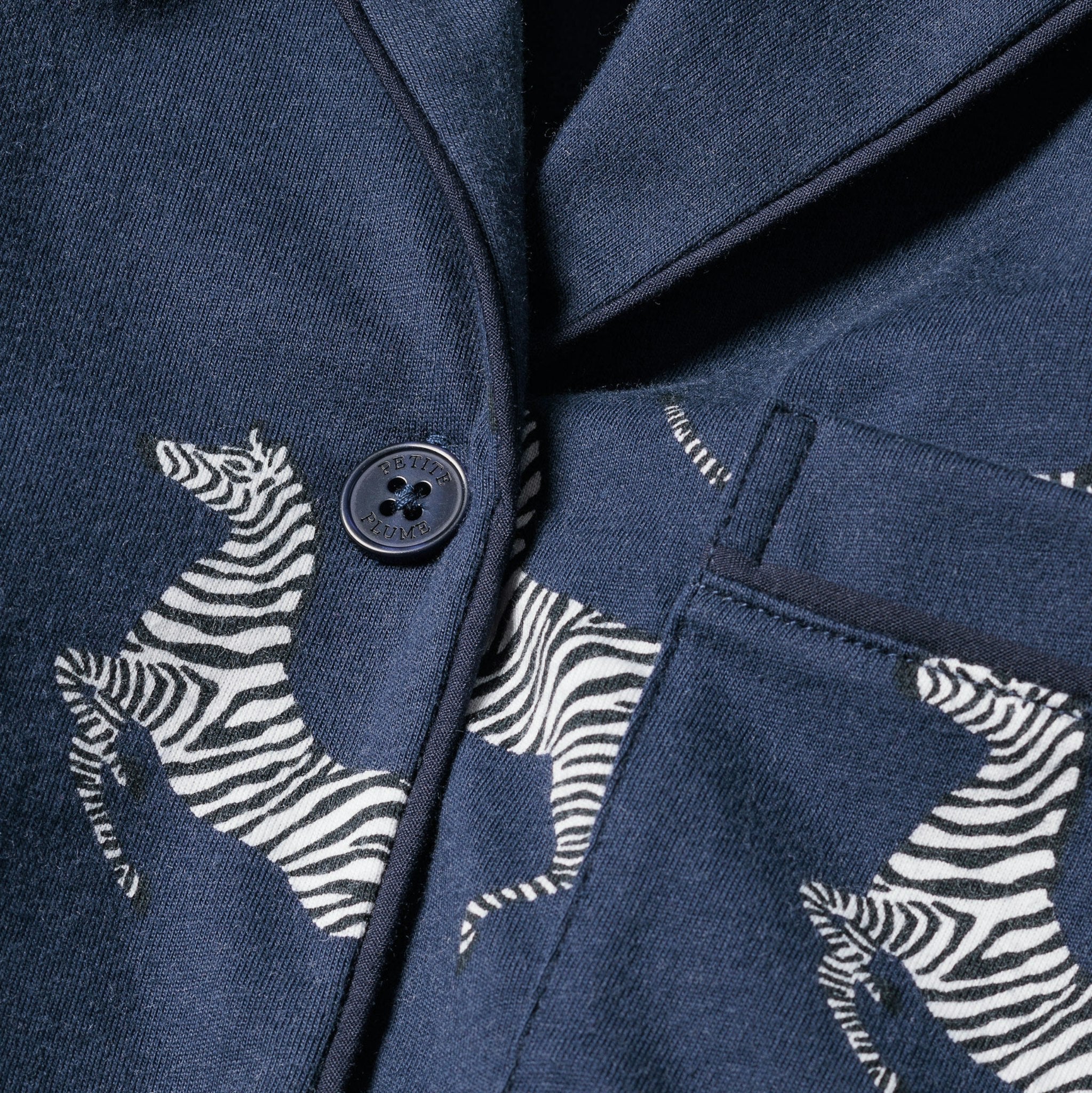 Navy blue jacket with zebra patterns and buttons on a dark background