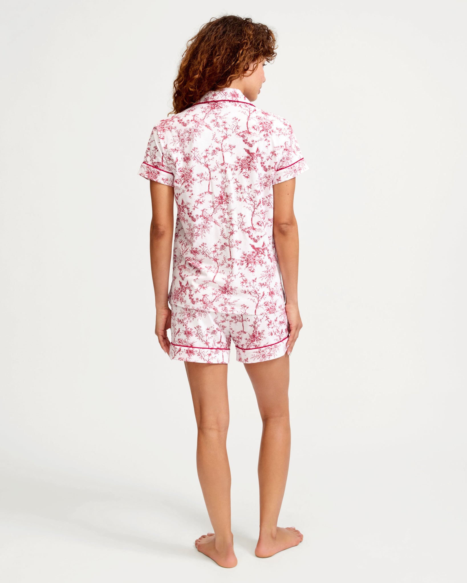 Woman wearing a pink floral pajama set on a white background