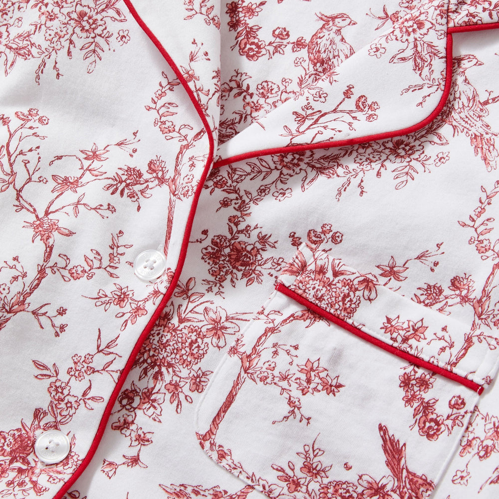 Red floral pattern on white fabric with 'Petite Plume' branding.