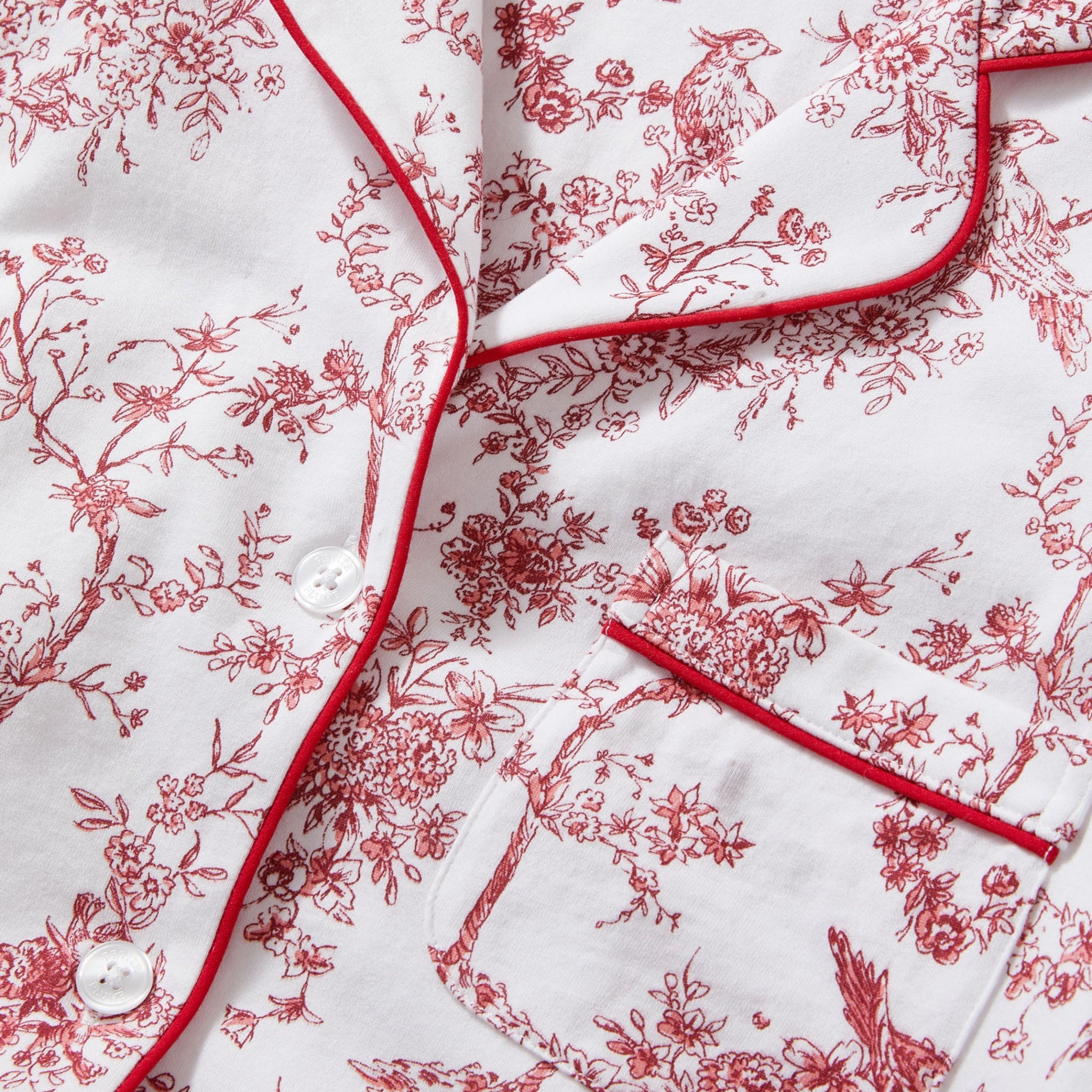 Red floral pattern on white fabric with 'Petite Plume' branding.