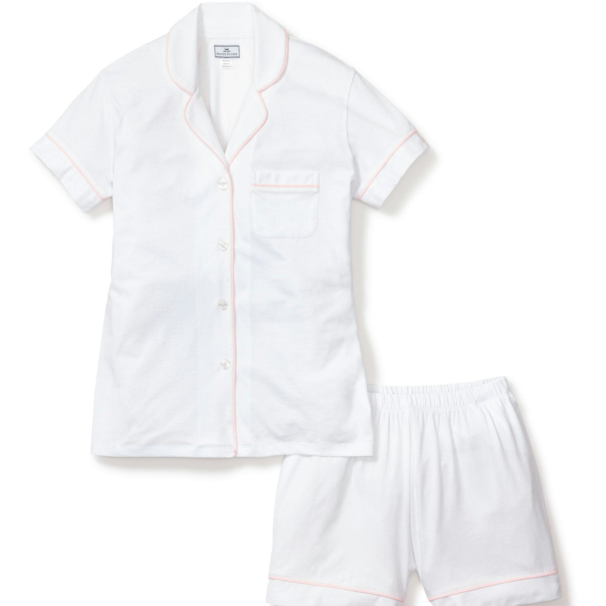 White pajama set with pink piping on a white background
