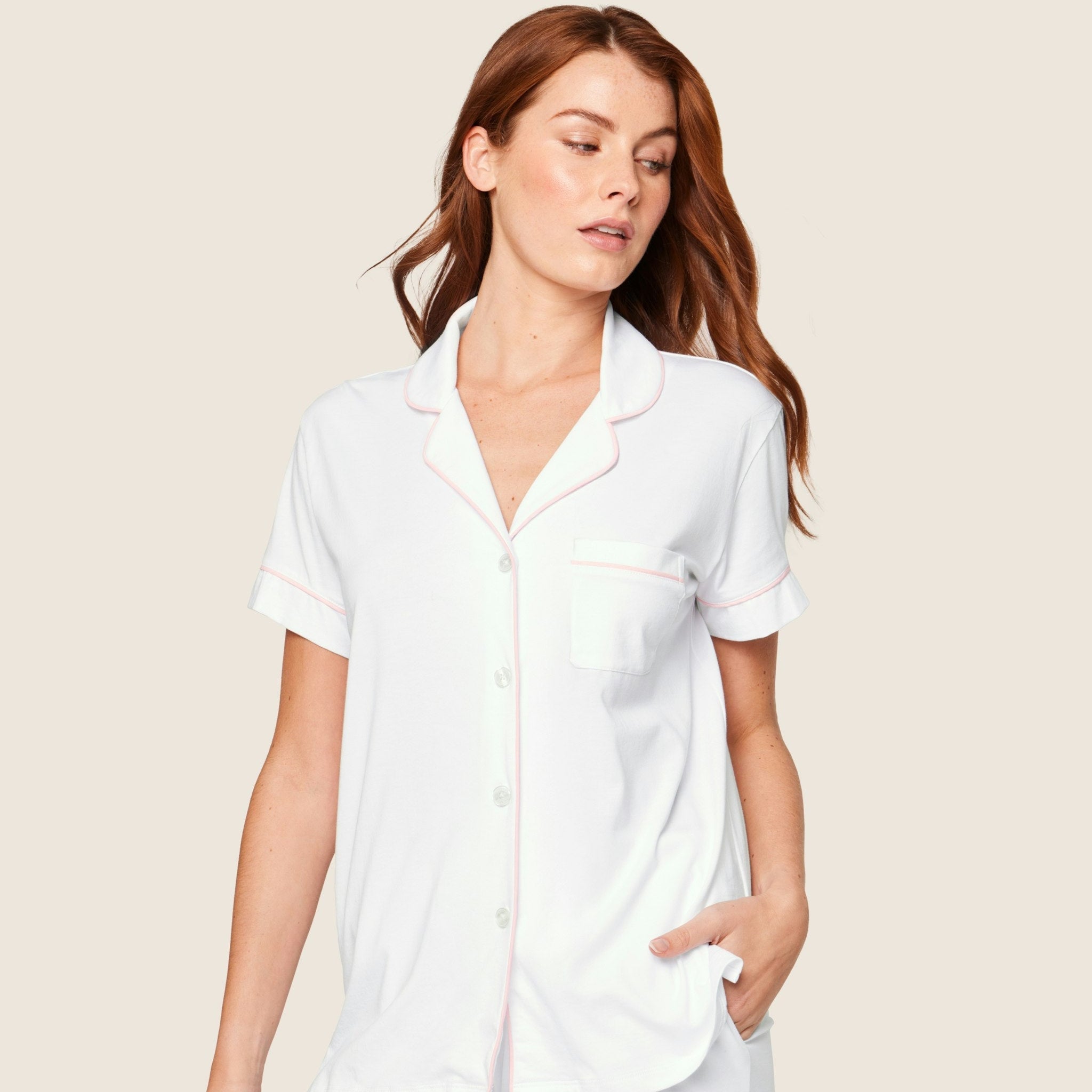 Woman wearing a white pajama set on a beige background