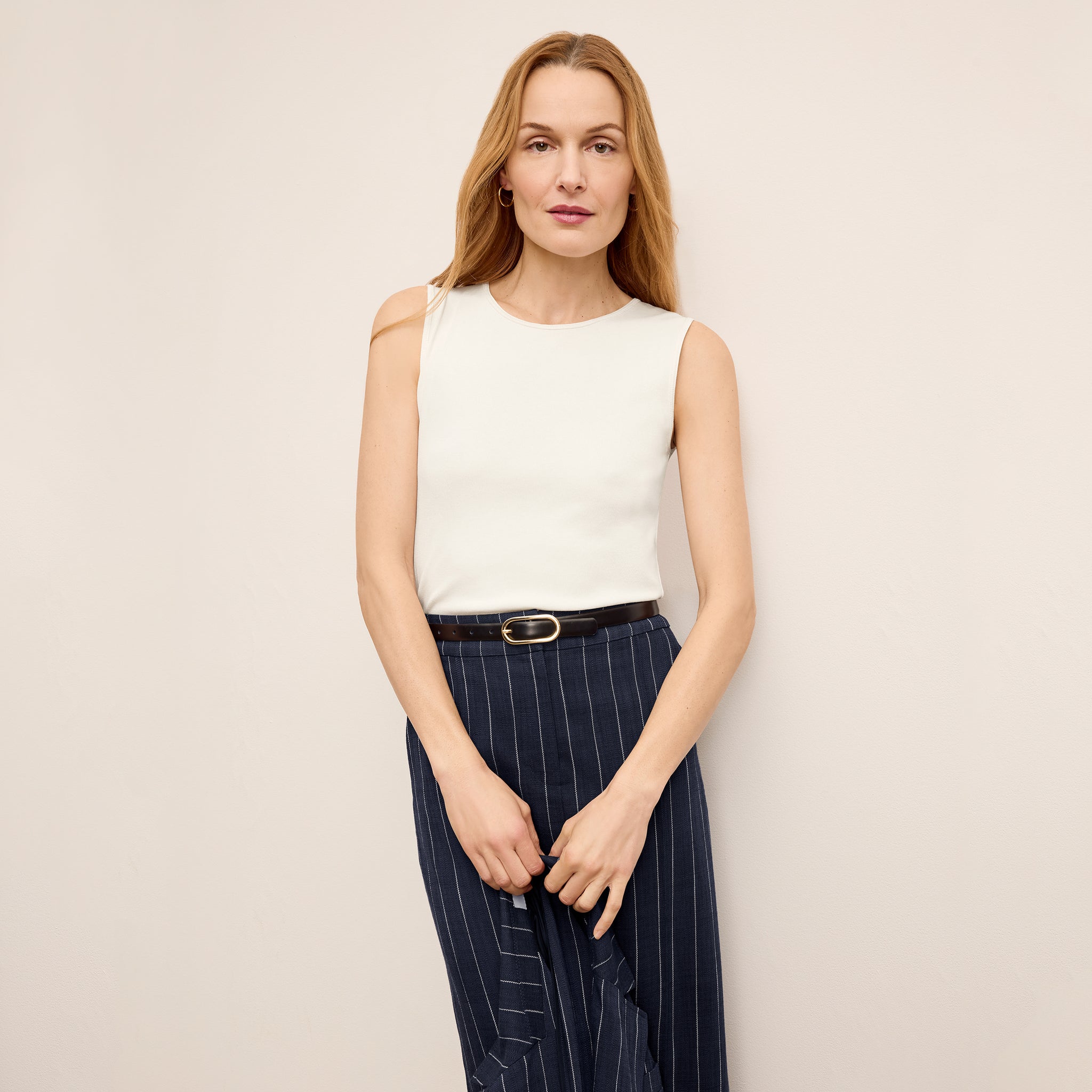 Front image of a woman standing wearing the paige top in fine ribbed cotton in ivory 