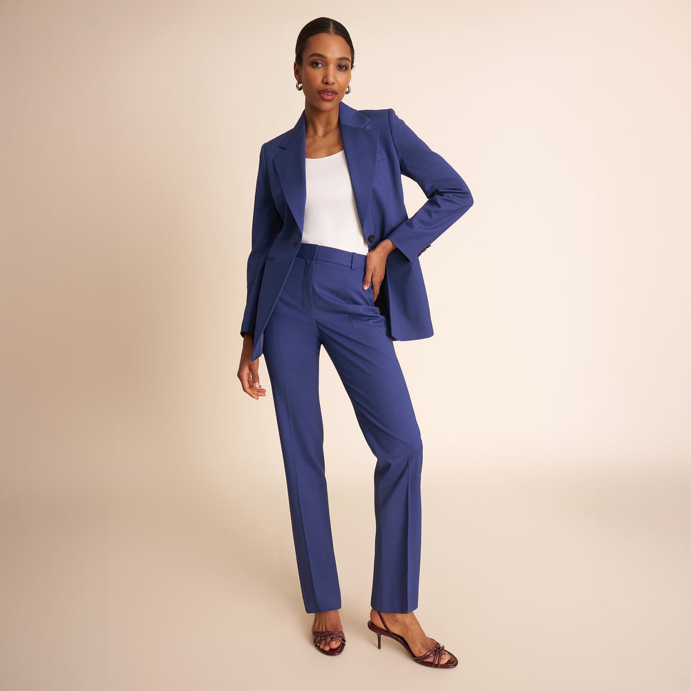 Woman wearing a blue suit with a white top on a beige background
