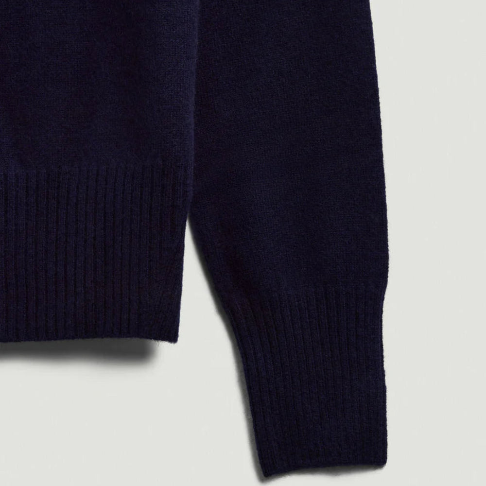 Close-up of a navy blue sweater sleeve on a light gray background