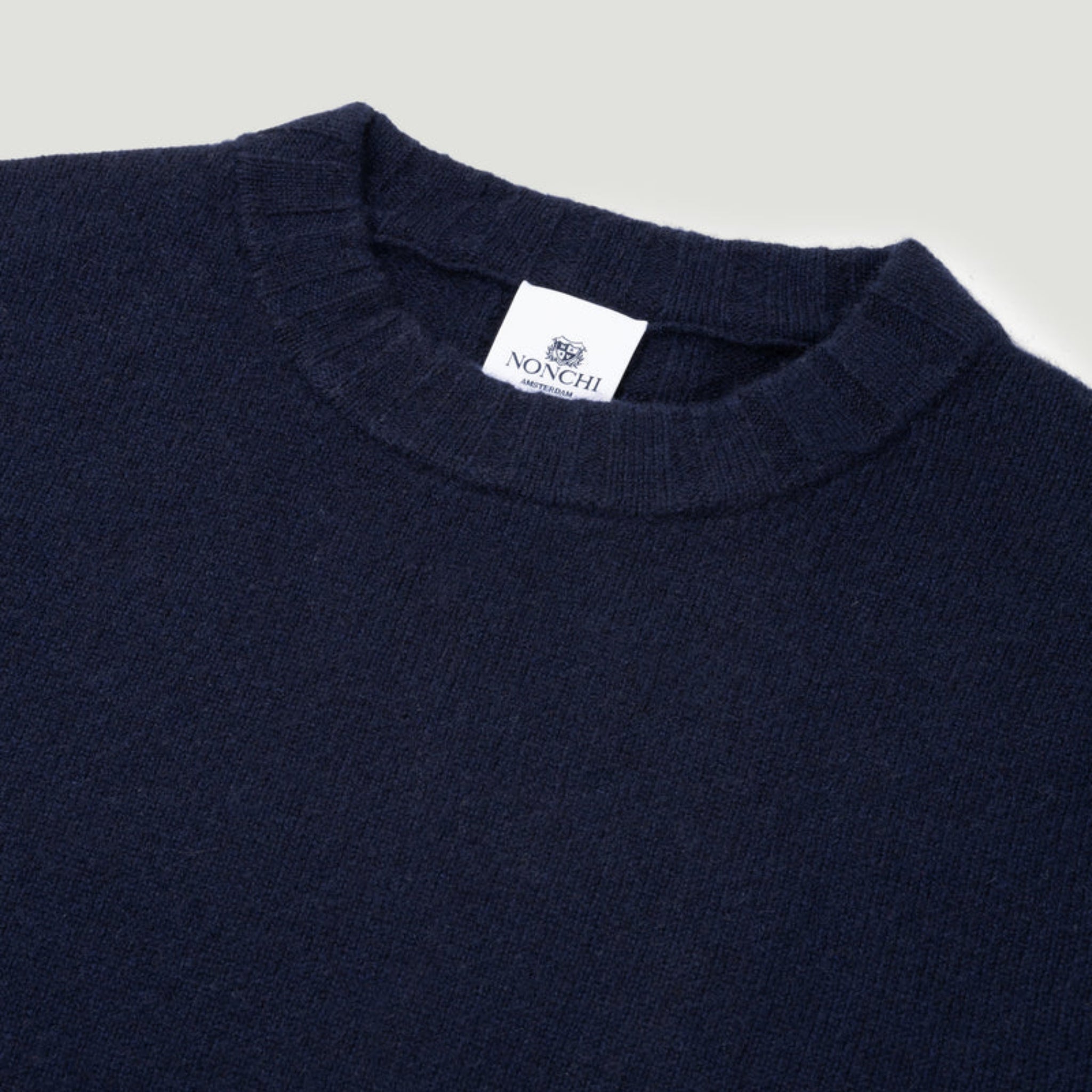 Navy sweater with a visible brand label on a light gray background