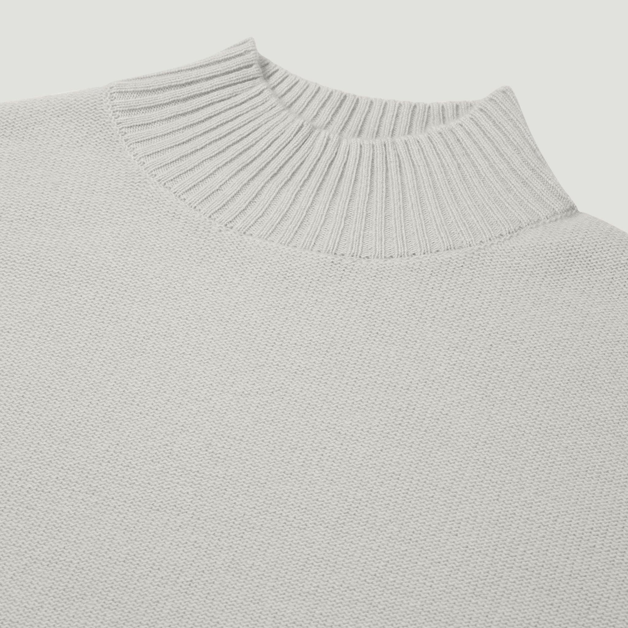 Close-up of a light gray sweater with a ribbed neckline on a white background
