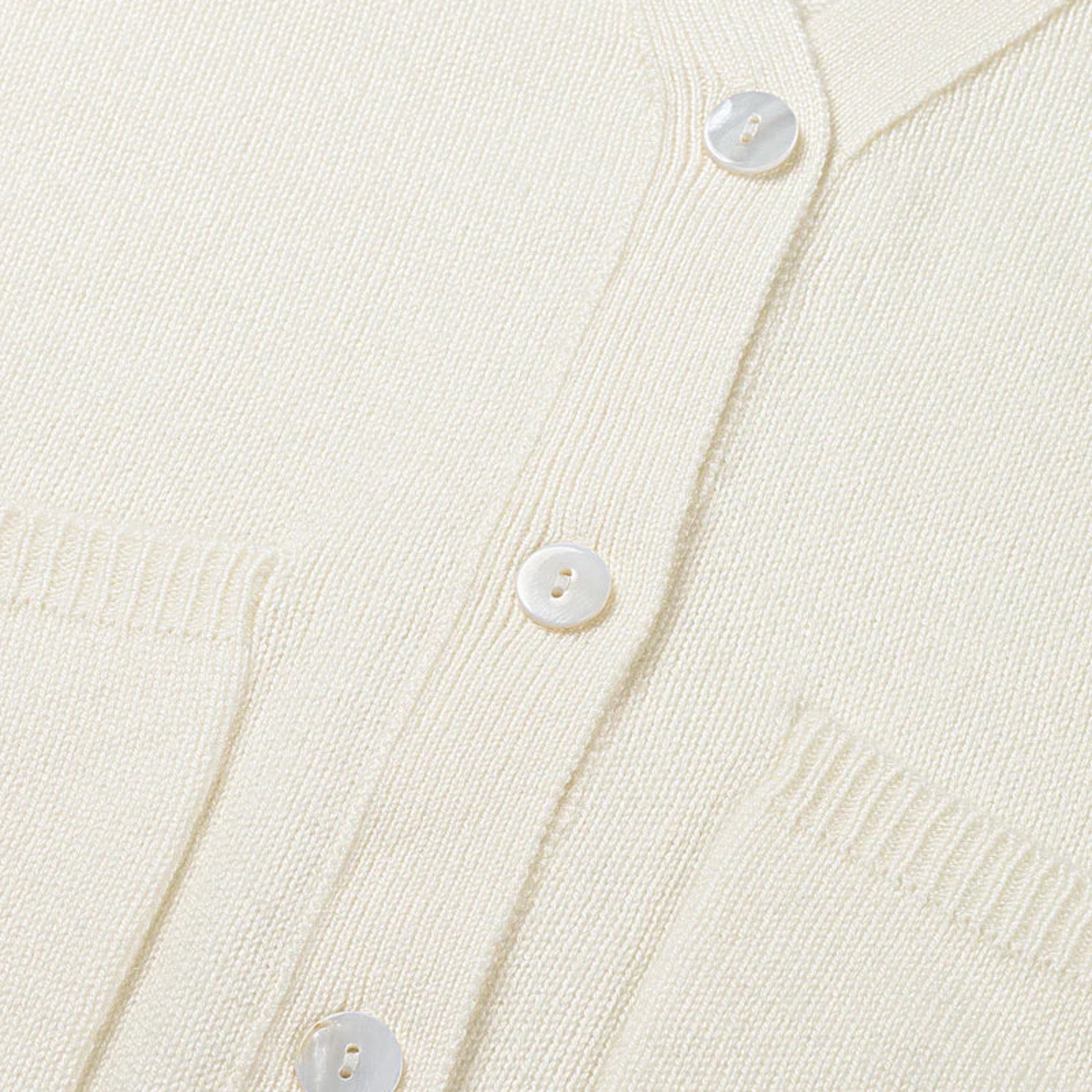 Close-up of a cream-colored cardigan with button details