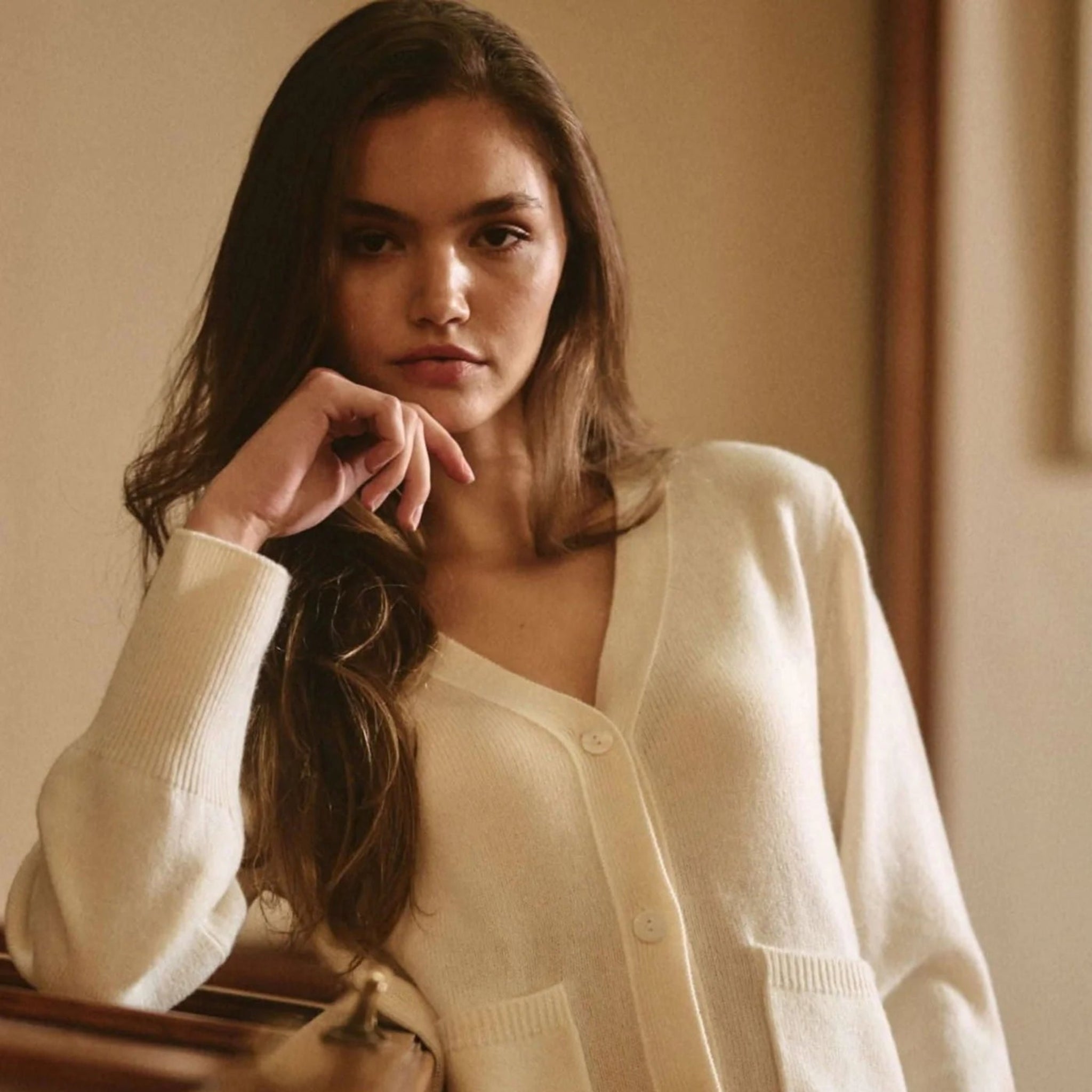 Woman wearing a white cardigan in a softly lit room
