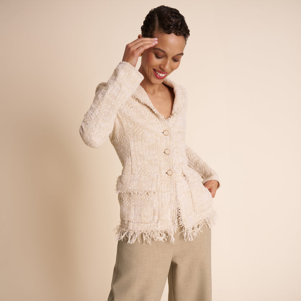 Woman wearing a cream-colored cardigan against a beige background