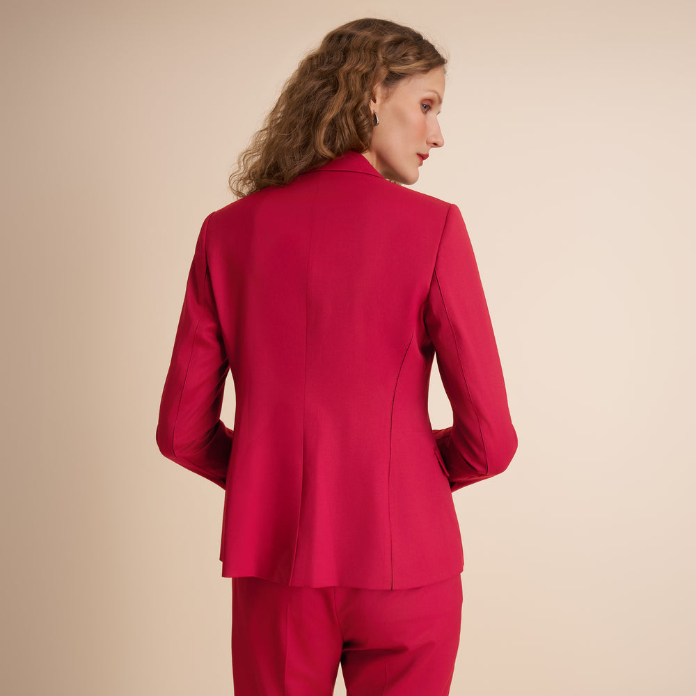Woman wearing a red suit against a beige background