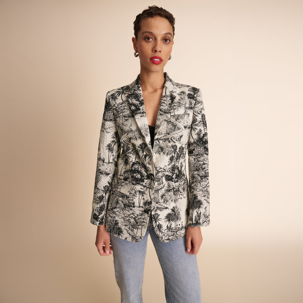 Woman wearing a patterned blazer against a beige background