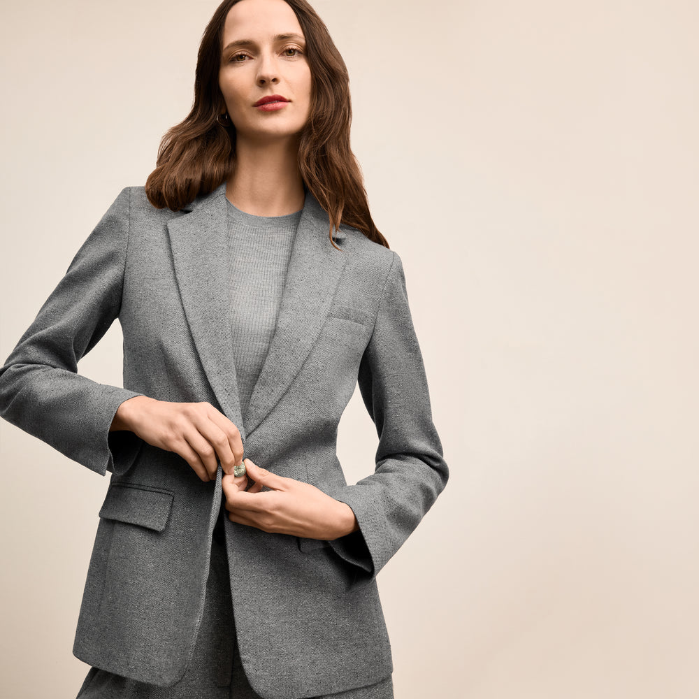 Woman wearing a gray blazer against a beige background