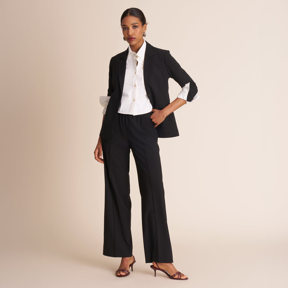 Woman wearing a black suit with a white shirt on a beige background