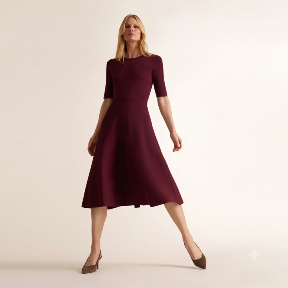 A woman modeling a short-sleeve, knee-length A-line dress in deep burgundy against a plain, warm off-white studio background.