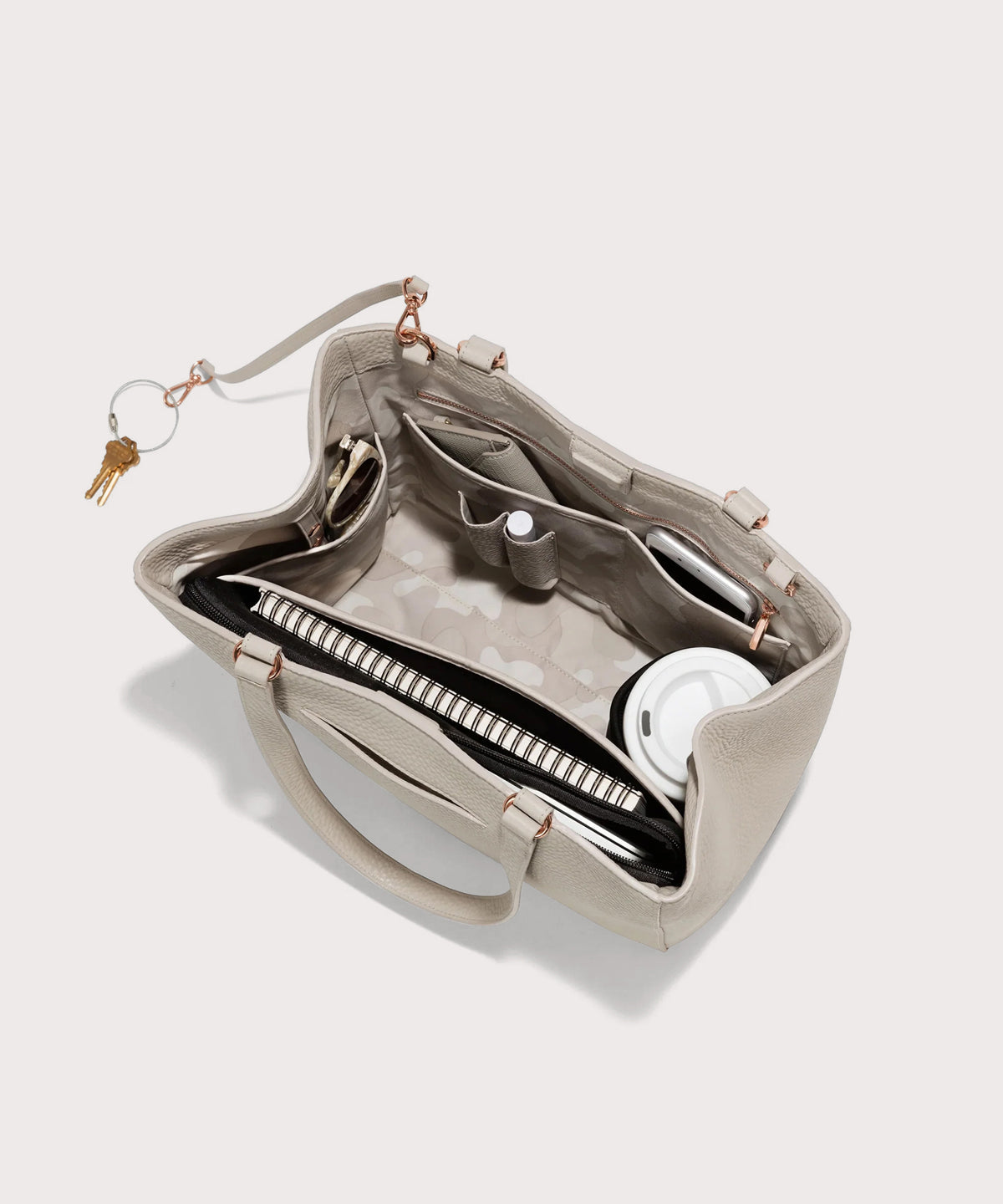 Open beige handbag with compartments on a light gray background