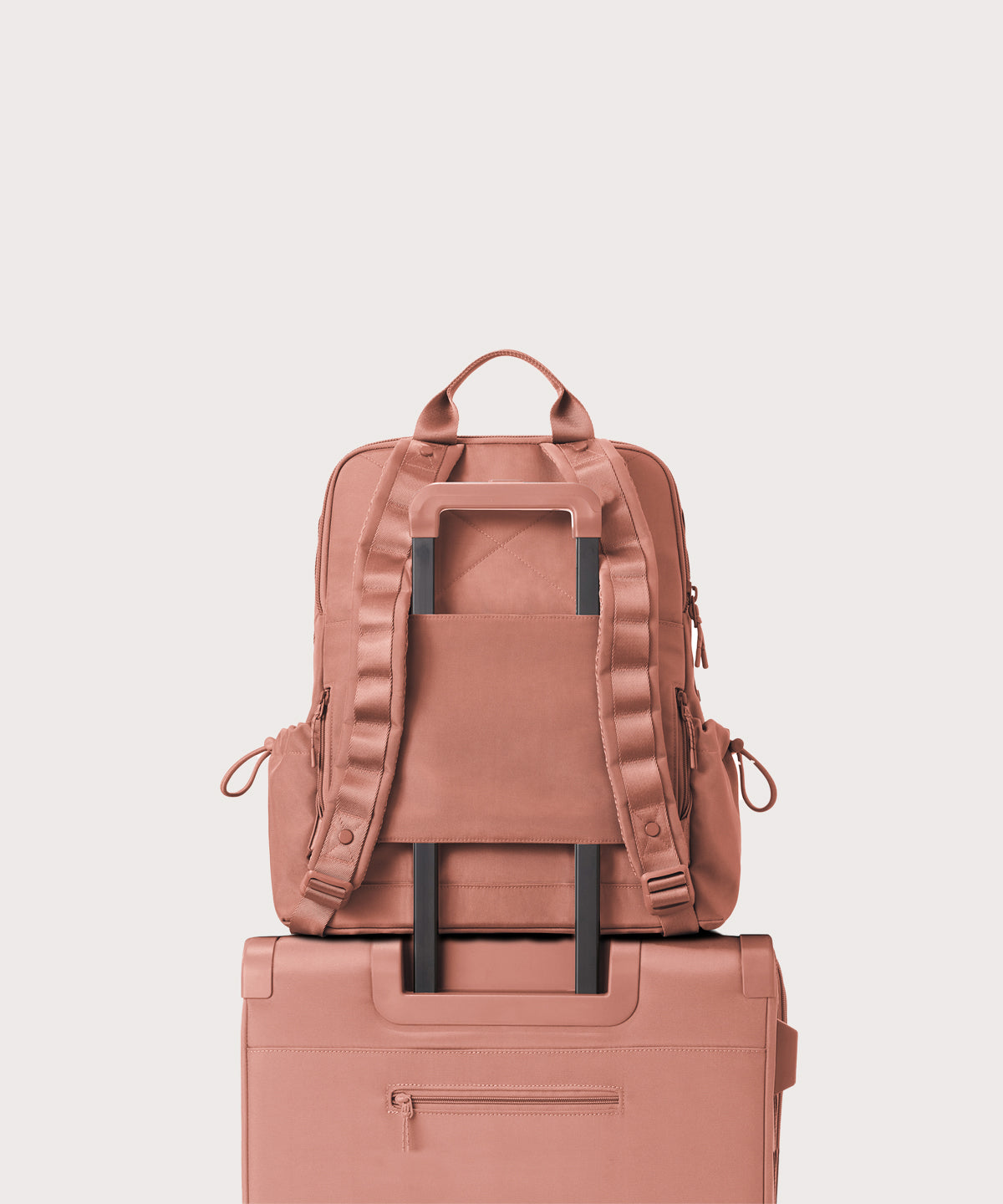 Pink backpack and suitcase stacked on a light gray background