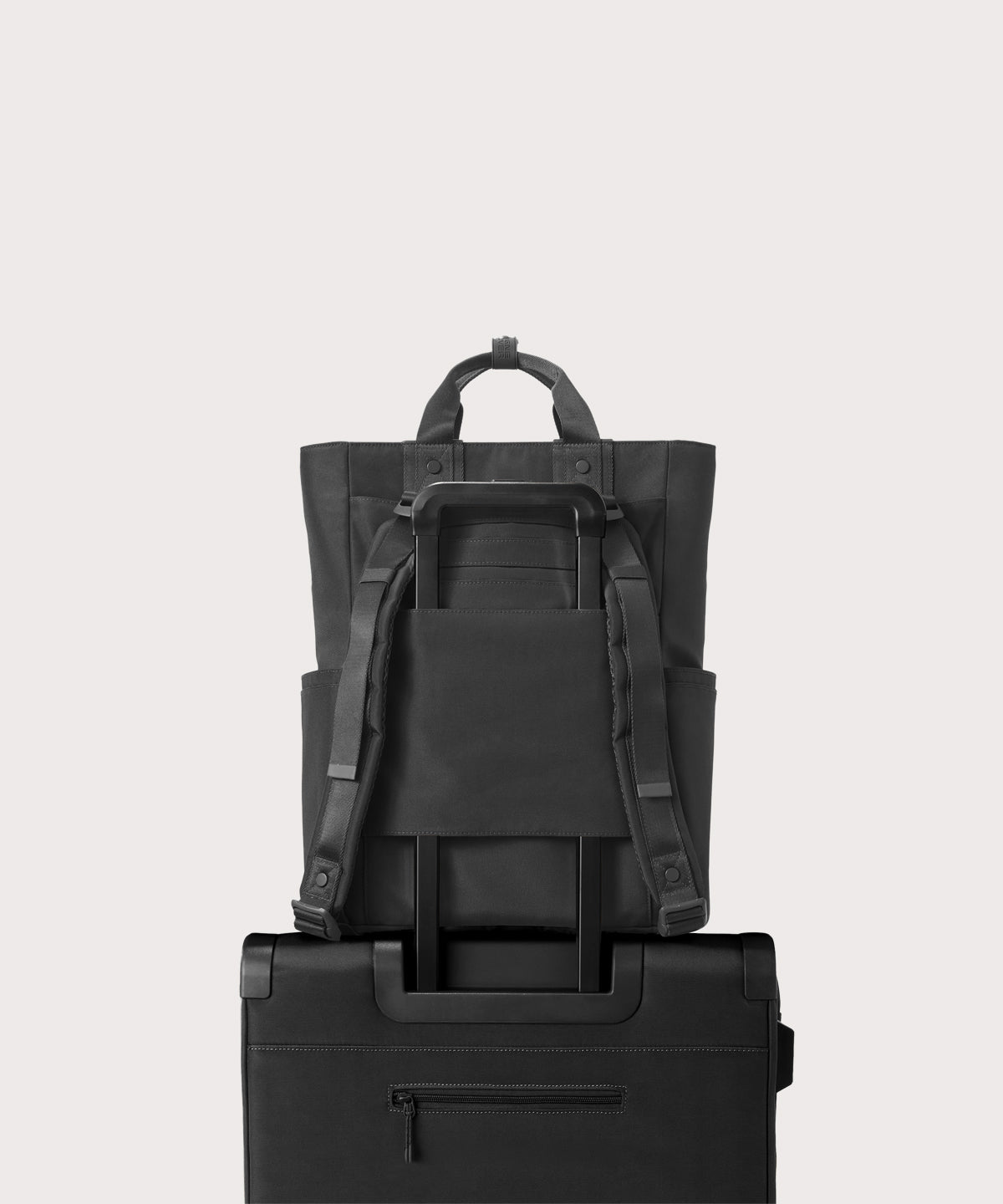 Black backpack and suitcase stacked on a light gray background