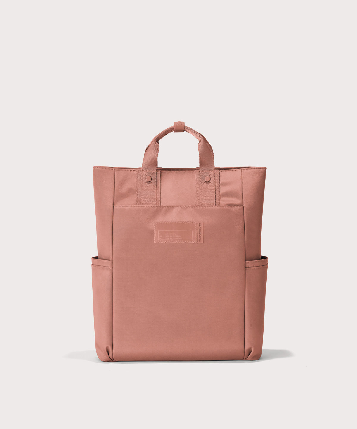 Pink tote bag with a visible brand label on a light gray background 