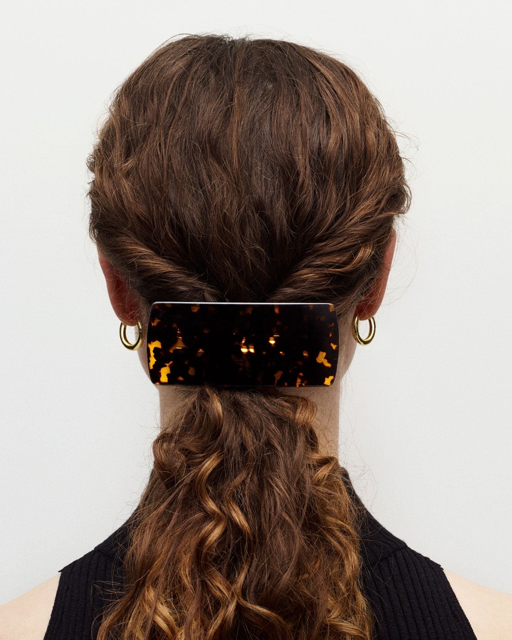 Person with braided hair wearing a tortoiseshell barrette against a white background