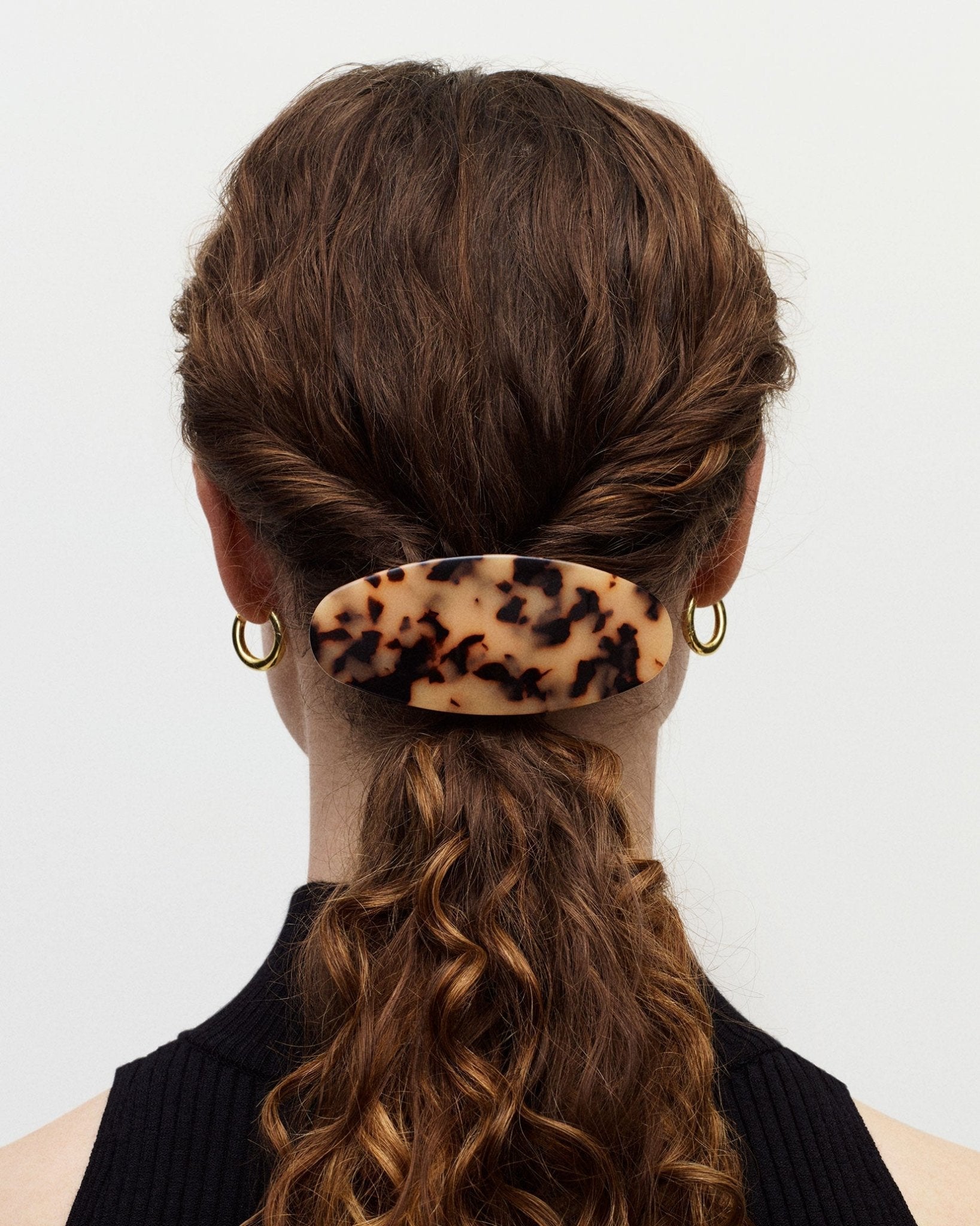 Person with a leopard print hair clip in their hair against a white background