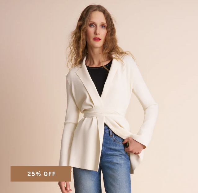 A woman modeling a cream-colored wrap-style cardigan with a tie waist over a black top and blue jeans, set against a solid beige background with a '25% OFF' banner in the bottom left corner.