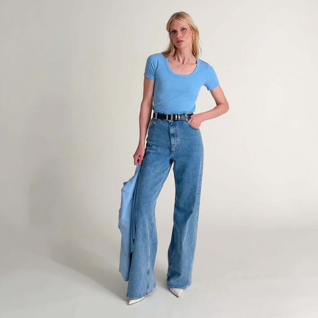 Woman wearing the Avi top in clear sky with jeans