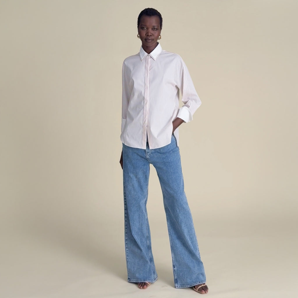 woman in tan button down with jeans.