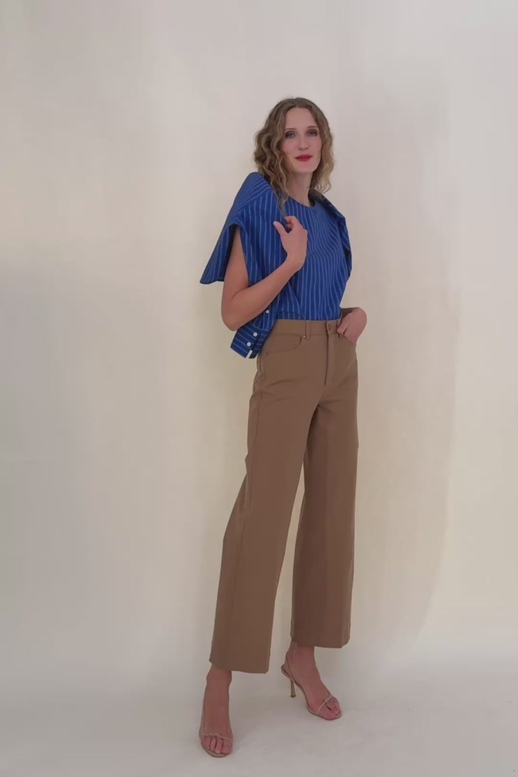 Woman wearing a blue striped shirt against a beige background