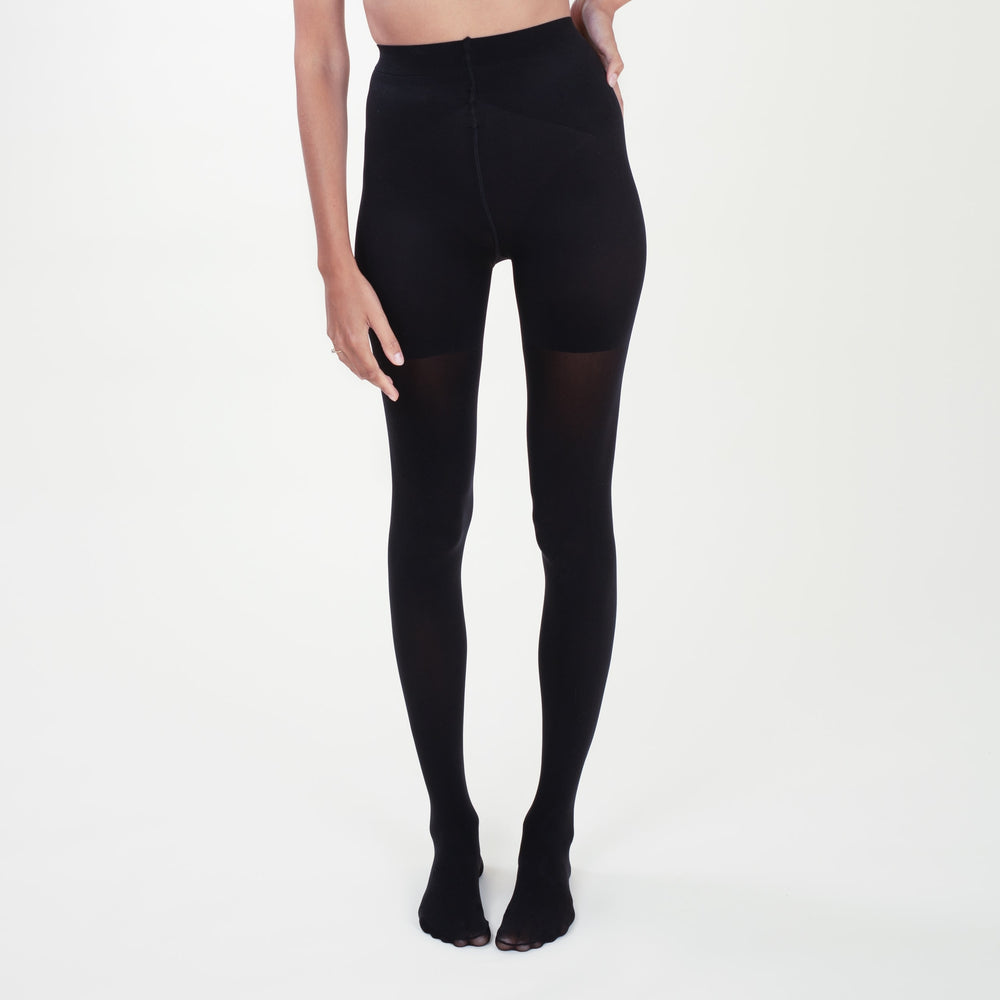 Front image of a woman standing wearing the Threads Opaque Tights in Black