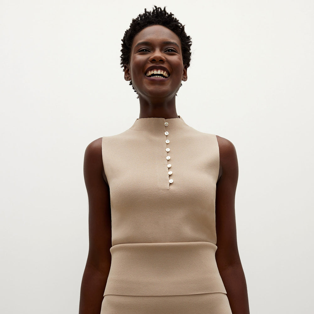 Front image of a woman standing wearing the Malki top in latte