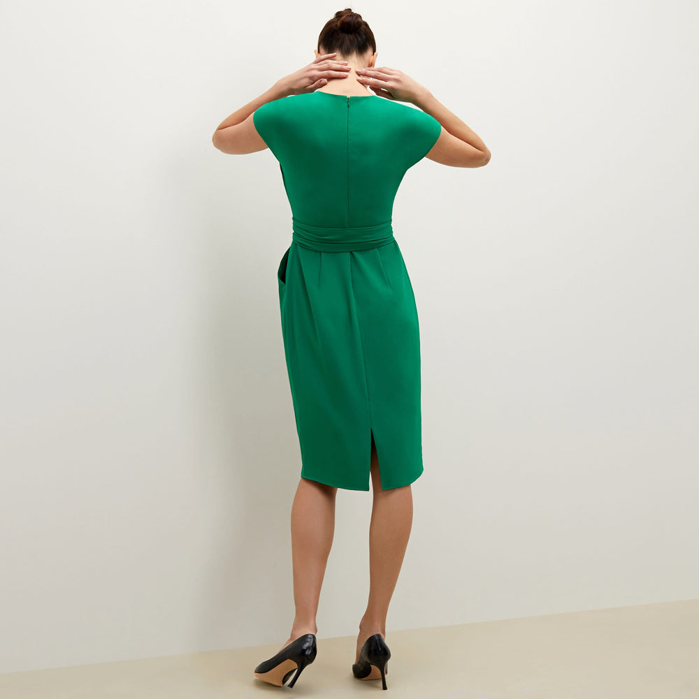 Back image of a woman standing wearing the Noel dress in emerald