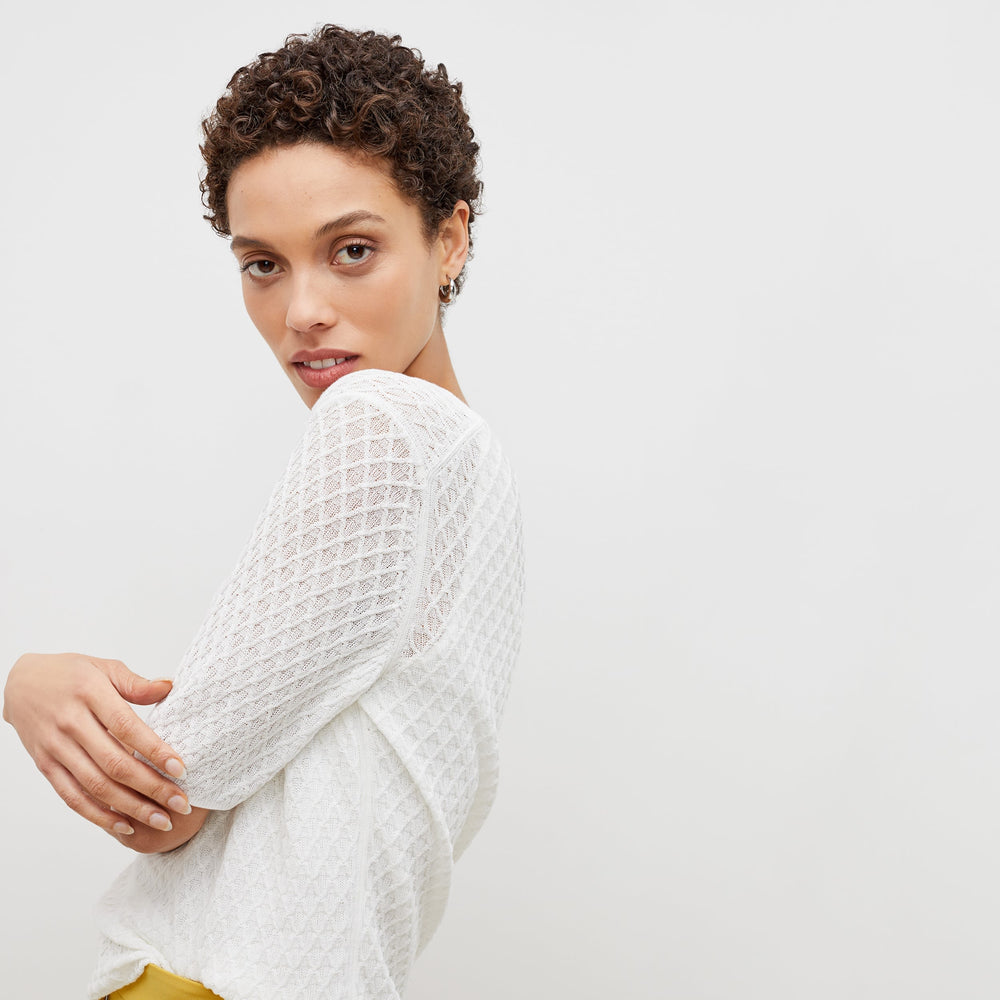 Side image of a woman standing wearing the natalie top in ivory