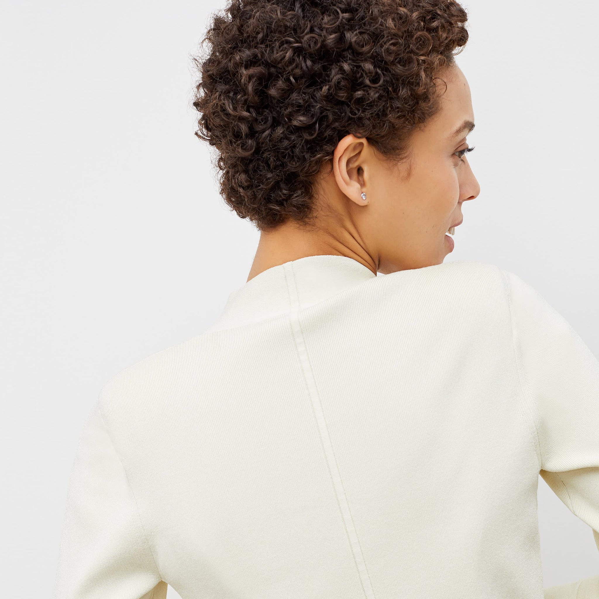 Back image of a woman standing wearing the sant ambroeus jardigan in ivory