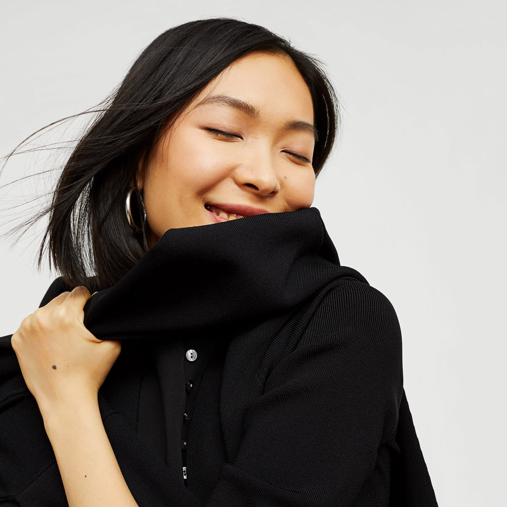 Detail image of a woman standing wearing the malki top in black