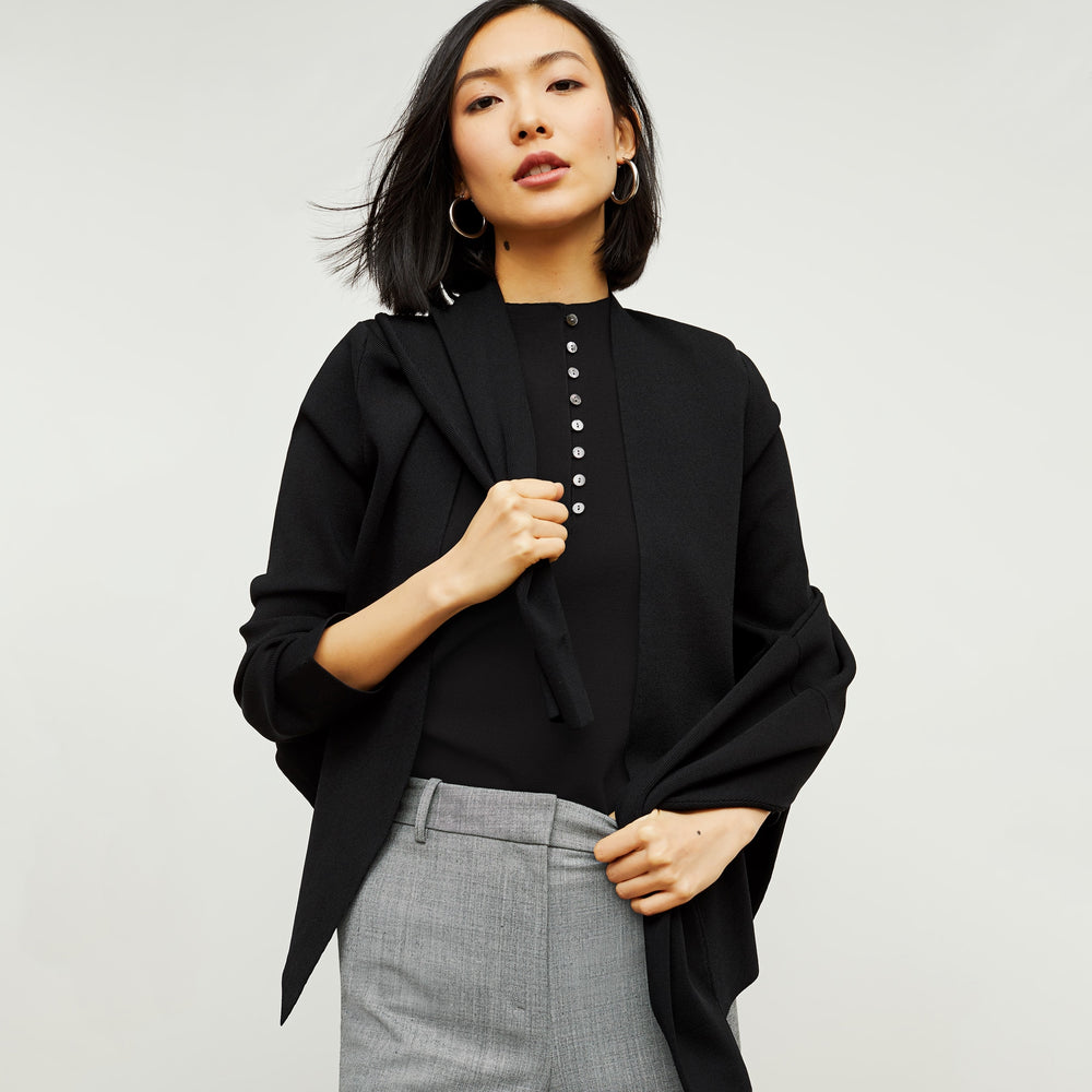 Front image of a woman standing wearing the malki top in black