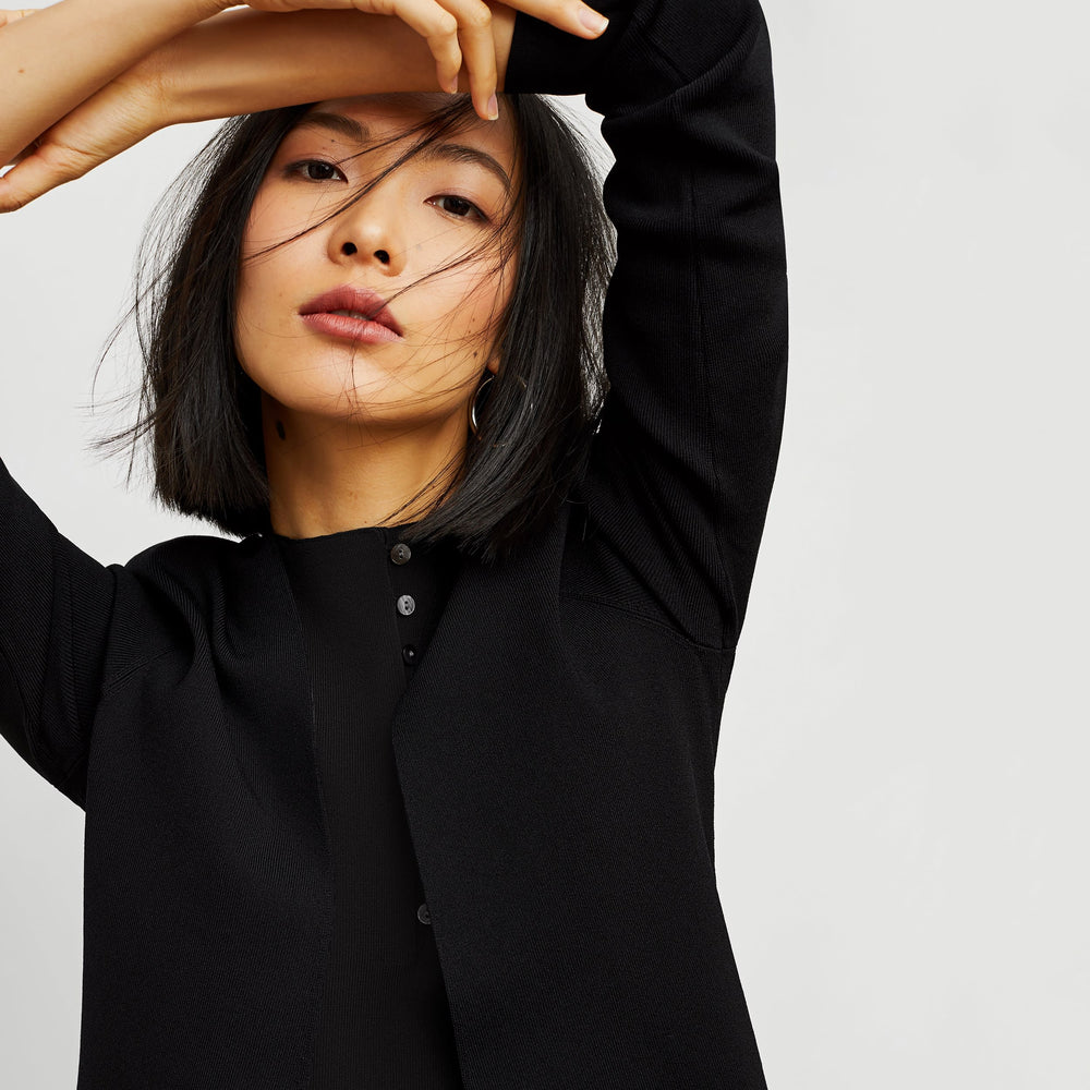 Front image of a woman standing wearing the malki top in black