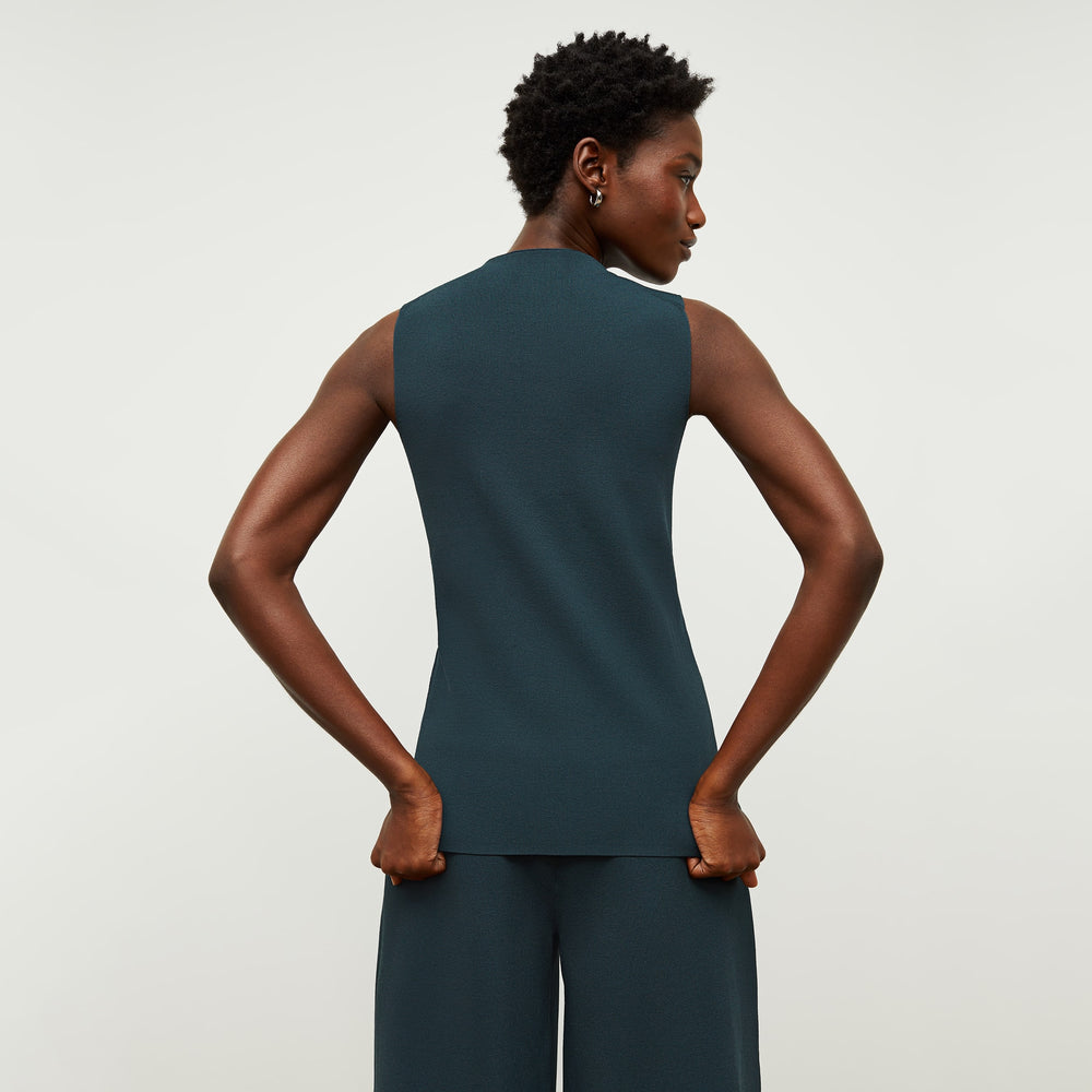 Back image of a woman standing wearing the malki top in deep sea