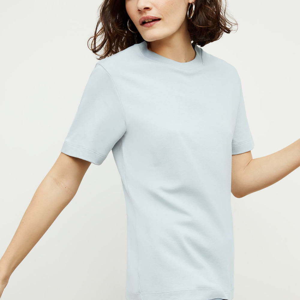 Side image of a woman standing wearing the Leslie T-Shirt—Compact Cotton in Sky Blue