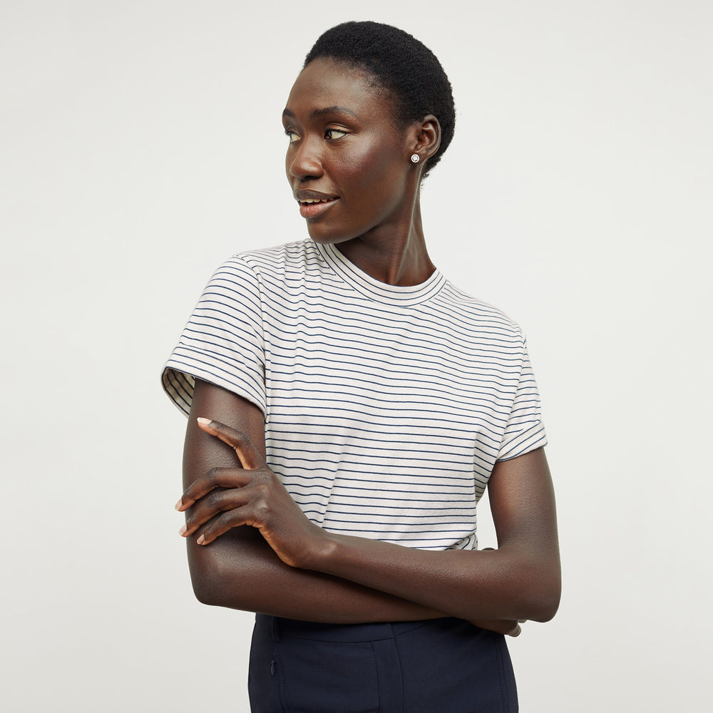 Front image of a woman standing wearing the Leslie T-Shirt—Thin Striped Cotton in Ivory / Coastline