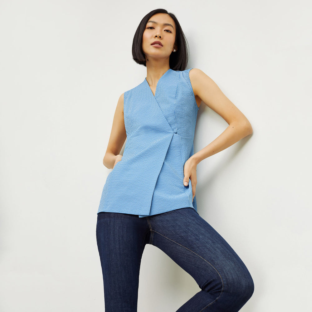 Front image of a woman standing wearing the ellen top in gingham seersucker in capri blue and white