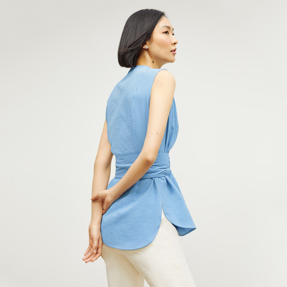 Back image of a woman standing wearing the ellen top in gingham seersucker in capri blue and white